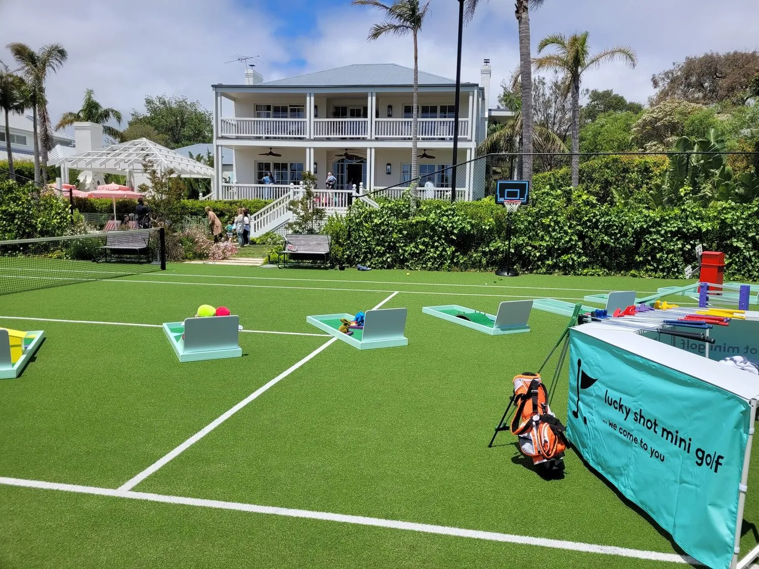 Mini golf set up on a private retreat lawn with Hampton-style venue backdrop