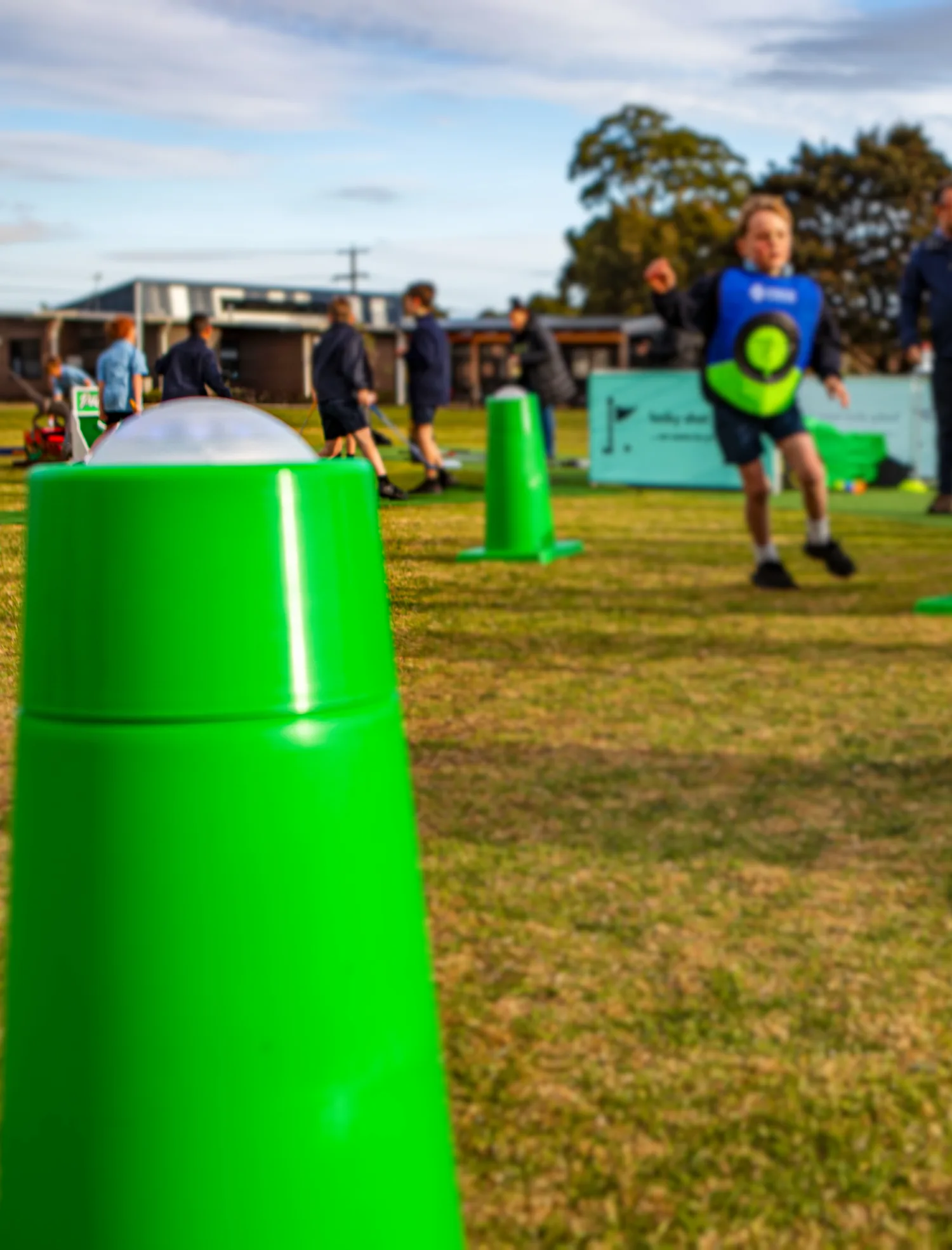 Children in target vests playing an Interactive Play System game between green sensor pods on grass