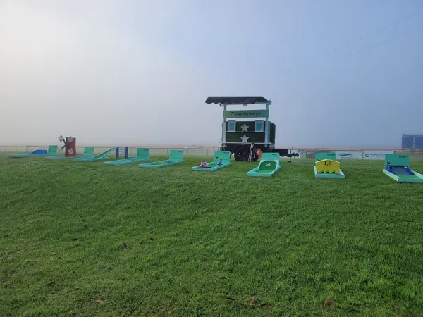 Lucky Shot Mini Golf branded trailer and course set up at a Melbourne beach during golden hour