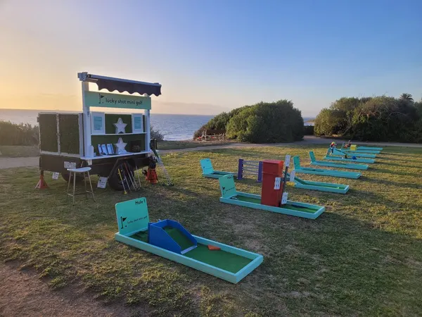 Lucky Shot Mini Golf course set up by the bay at a Melbourne outdoor event at sunset
