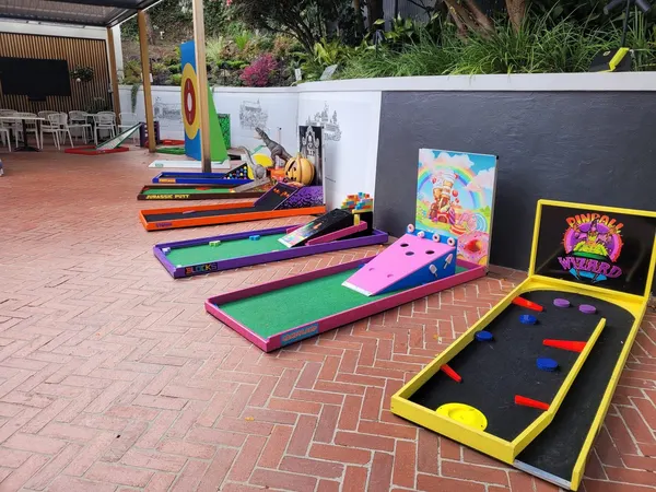 Lucky Shot Mini Golf holes set up on wooden flooring inside a Melbourne workplace with putters lined up ready to play