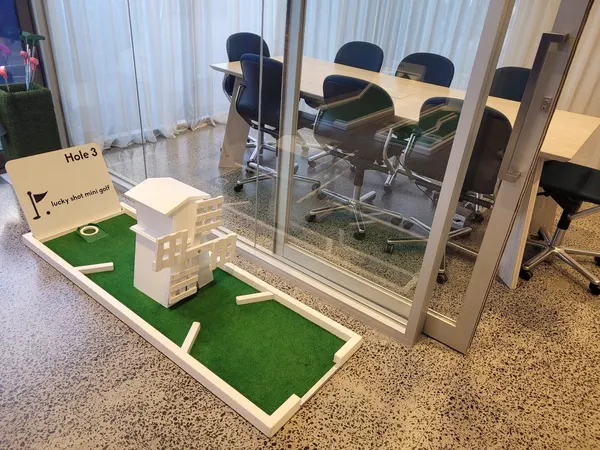 Lucky Shot Mini Golf course weaving through an active Melbourne office floor with team member at desk in background