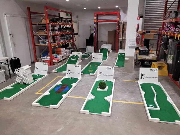Lucky Shot Mini Golf course running between library bookshelves in a Melbourne corporate space