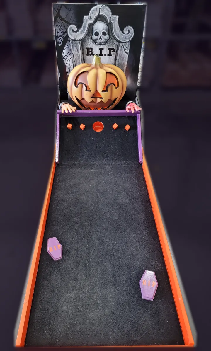 Lucky Shot's Halloween mini golf hole: a tombstone backboard, a carved pumpkin with two hands gripping the ledge, and two coffin obstacles on a black and orange lane